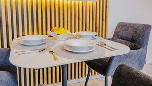 A dining table with white plates, gold cutlery, and a bowl of fruit. - Rezidence Petra Voka 208 by Interhome (Trebon)