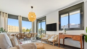 A modern living room with a sofa, wicker chairs, a dining table, and a desk.
