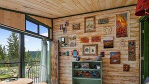 Une pièce aux murs en bois, dotée de grandes fenêtres et ornée de diverses œuvres d’art.
