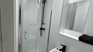 Une salle de bain moderne avec une douche à parois de verre, un lavabo blanc et un miroir au-dessus.