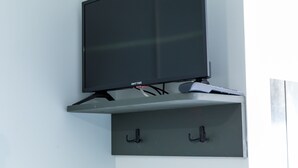 Un téléviseur à écran plat fixé au mur, avec une étagère en dessous.