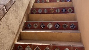 Uma escadaria com ladrilhos estampados e um portão de metal no topo.
