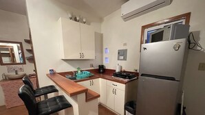 Uma cozinha compacta com geladeira, pia e um espaço de bar com dois banquinhos.