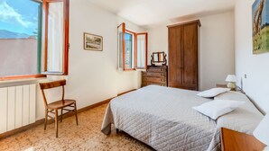 A bedroom with a bed, a chair, a dresser, and a window.