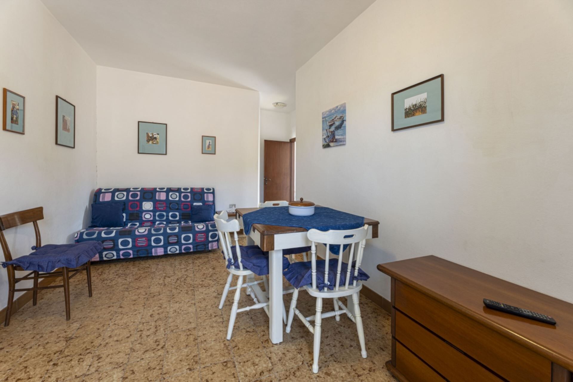 Una habitación pequeña y acogedora con una mesa de comedor, dos sillas, un sofá y un aparador de madera.