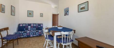 Una habitación pequeña y acogedora con una mesa de comedor, dos sillas, un sofá y un aparador de madera.