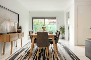 Un coin repas avec une table en bois, des chaises et un tapis rayé noir et blanc.