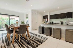 A modern kitchen with dark cabinets, a built-in oven, and a countertop with a coffee machine.