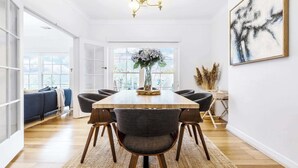 Un coin repas avec une table en bois, six chaises et un vase de fleurs.