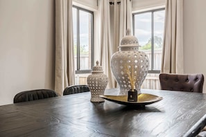 A dining table with a decorative centerpiece, two vases, and a chair.