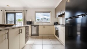 A modern kitchen with a stainless steel dishwasher, a black refrigerator, and a window with a view of the outside.
