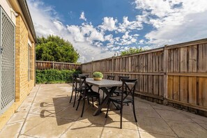 Eine Terrassengaststätte mit Tisch und Stühlen, einem Holzzaun und einer Backsteinmauer.