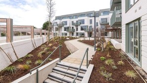 Un moderno edificio condominiale con cortile interno, area relax all'aperto e una scalinata che conduce all'ingresso.