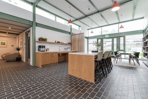 A modern kitchen with a central island, bar stools, and a dining area with a view.