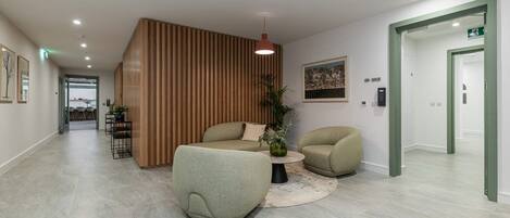 A modern lobby with a reception desk, seating area, and a staircase.