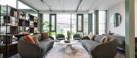 A modern living room with two grey sofas, a coffee table, and a bookshelf.