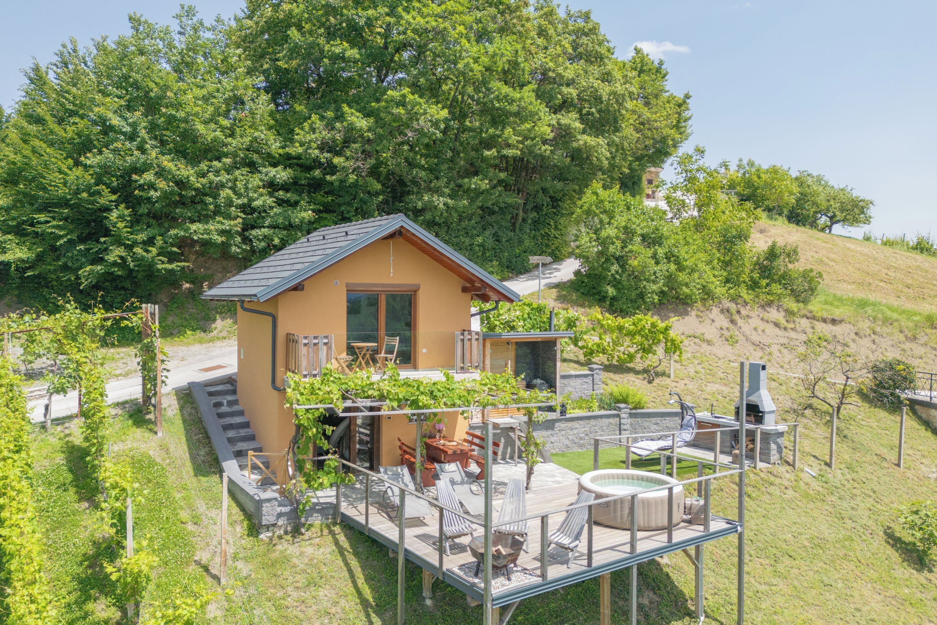 A modern house with a deck, outdoor seating, and a hot tub.
