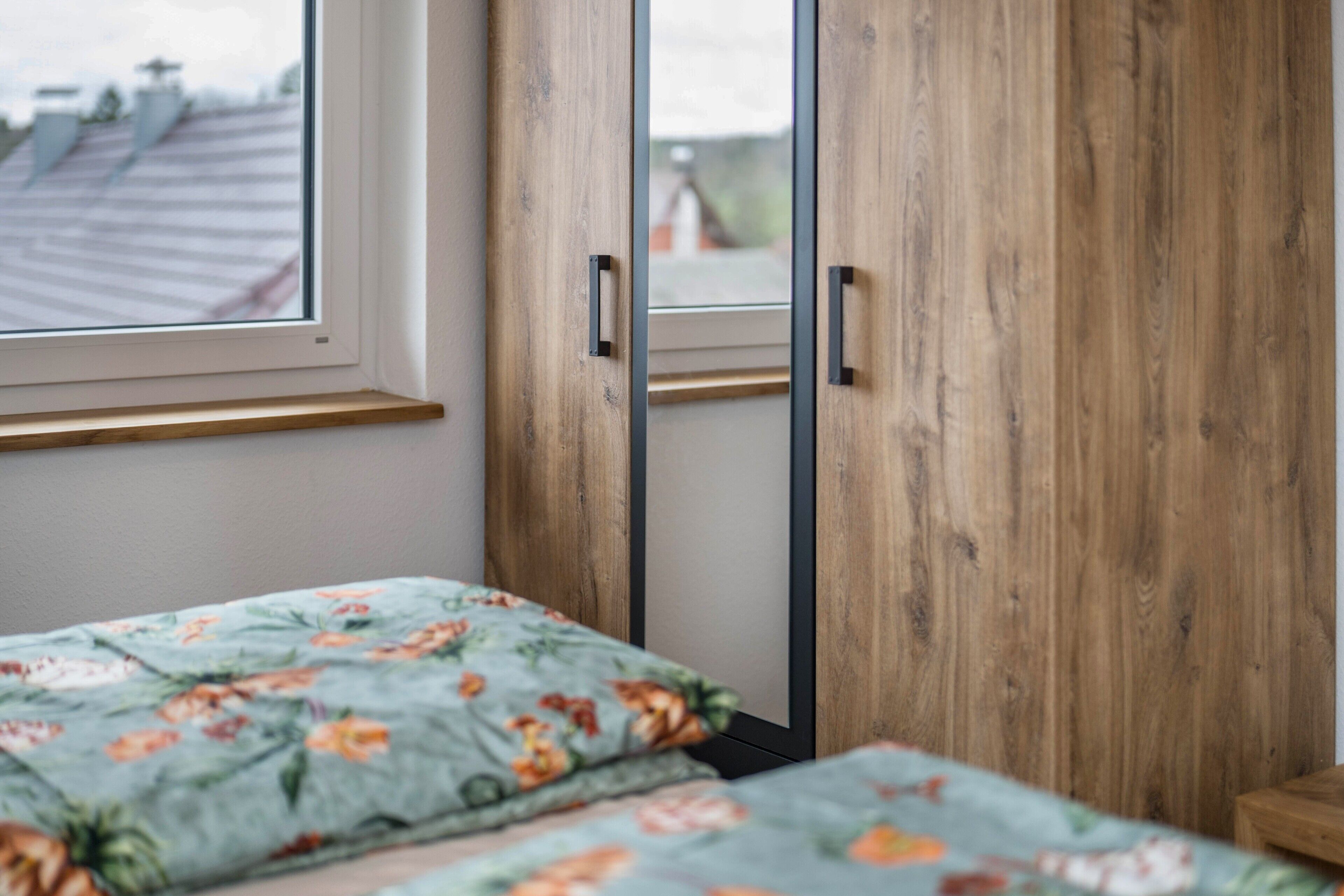 Un dormitorio con cama, armario de madera y ventana con vista a un edificio.