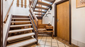 A wooden staircase with a cushioned handrail, a small wooden bench, and a door with a picture frame. - Holiday Home 'Ferienwohnung Loy' with Private Terrace, Private Garden and Wi-Fi (Rastede)