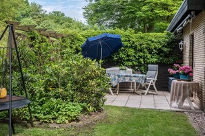 A patio with a table and chairs, a swing set, and a wooden fence. - Holiday Home 'Ferienwohnung Loy' with Private Terrace, Private Garden and Wi-Fi (Rastede)