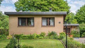 A single-story brick house with a well-maintained lawn, a small garden, and a visible number '2' on the front door. - Holiday Home 'Ferienwohnung Loy' with Private Terrace, Private Garden and Wi-Fi (Rastede)