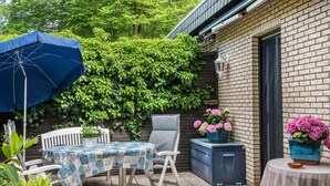 An outdoor patio with a table and chairs, a blue umbrella, and potted plants. - Holiday Home 'Ferienwohnung Loy' with Private Terrace, Private Garden and Wi-Fi (Rastede)