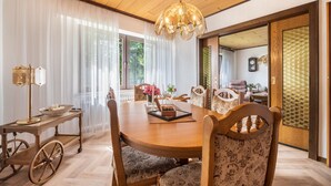 A dining area with a wooden table, chairs, a chandelier, and a view through a shoji screen. - Holiday Home 'Ferienwohnung Loy' with Private Terrace, Private Garden and Wi-Fi (Rastede)