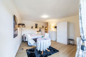 A bedroom with a bed, bedside table, lamp, wardrobe, and a small table with a chair.