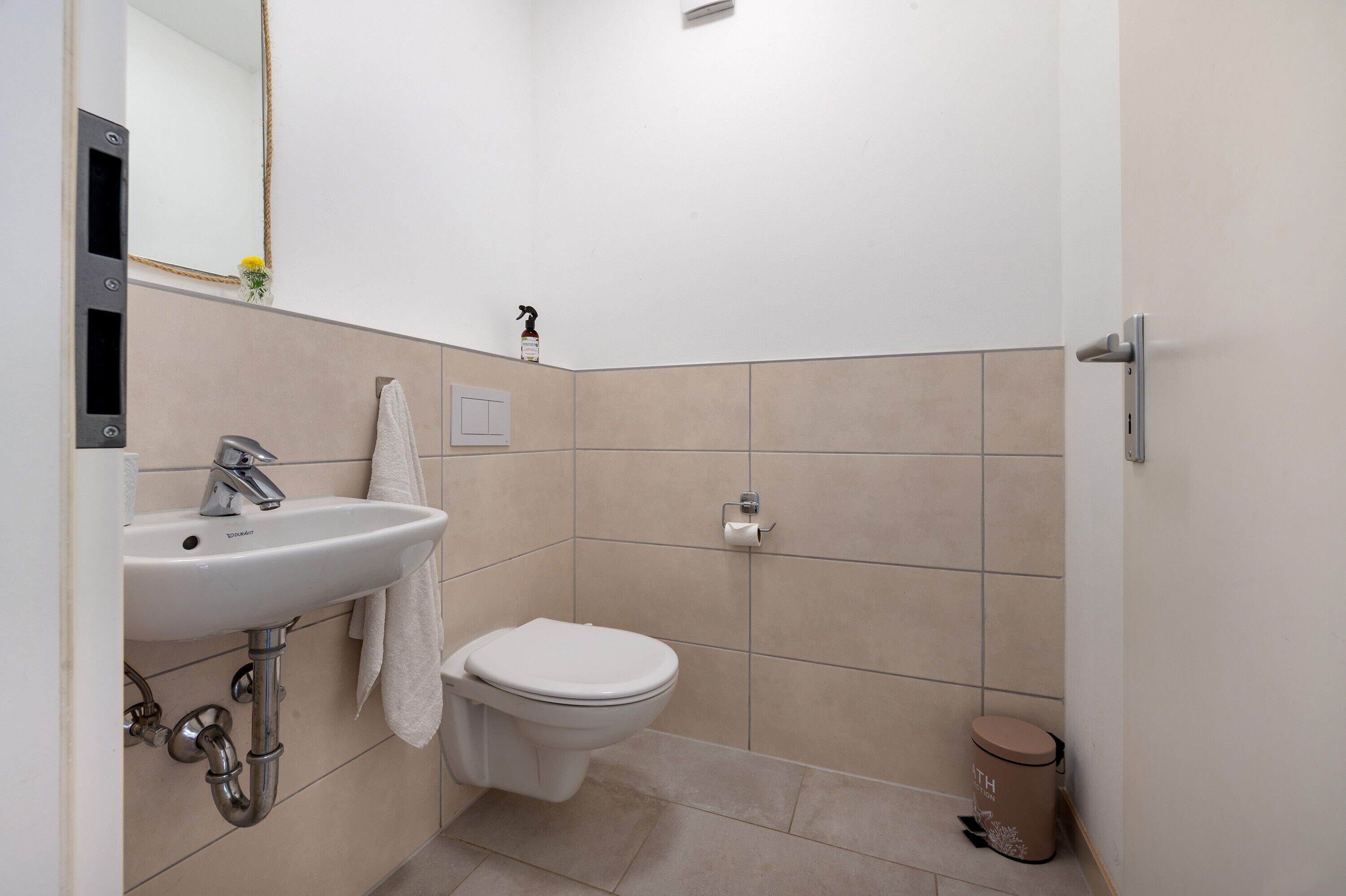 Une salle de bain équipée d’un lavabo, de toilettes et d’une poubelle.