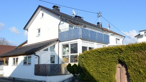Ein zweistöckiges Haus mit Balkon, Satellitenschüssel und umzäunter Garten.