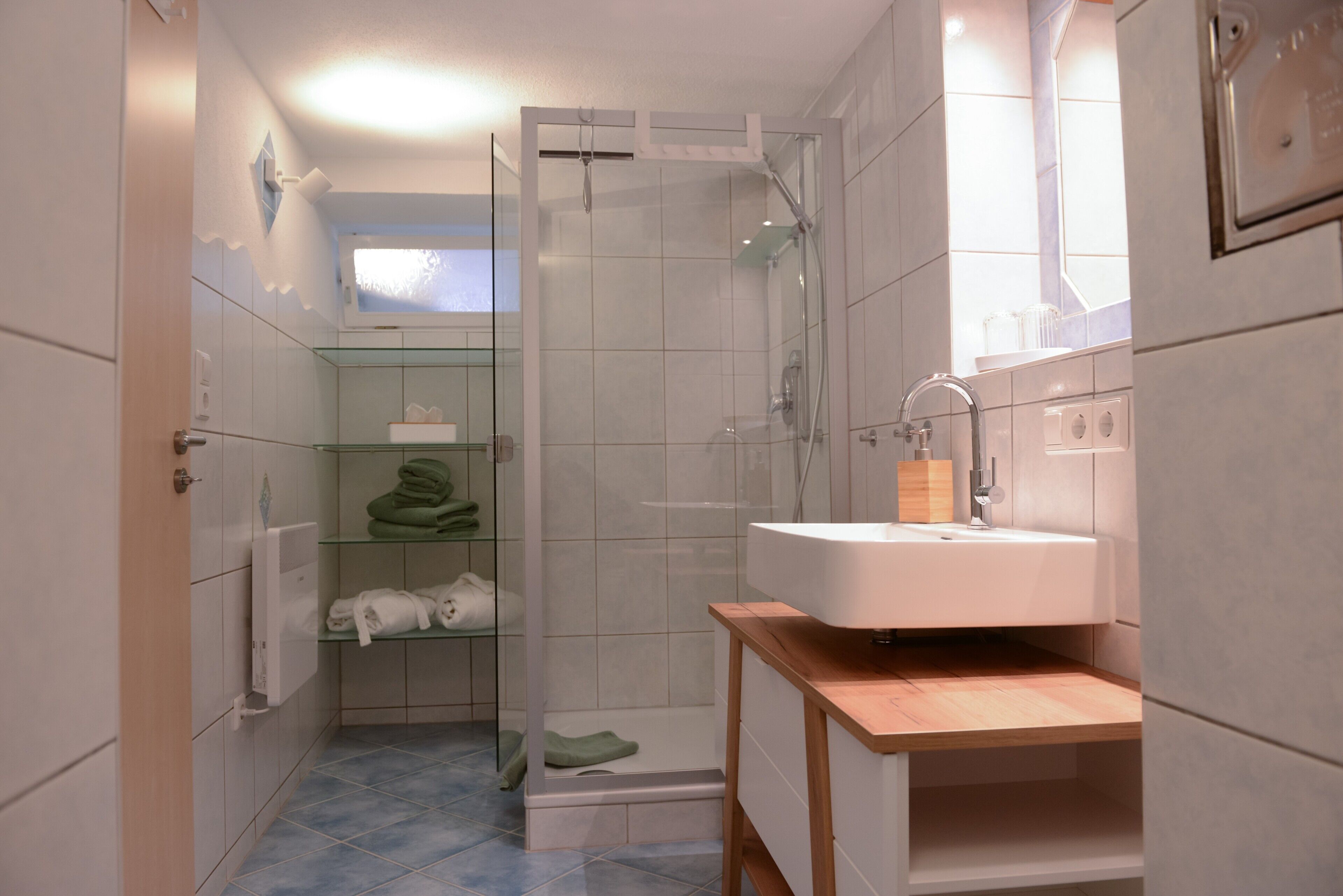 Une salle de bain avec une douche à parois de verre, un lavabo et un meuble-lavabo en bois.