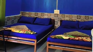 A room with two beds, a ceiling fan, and a patterned wall. - Rudra Adventures (Narendranagar)