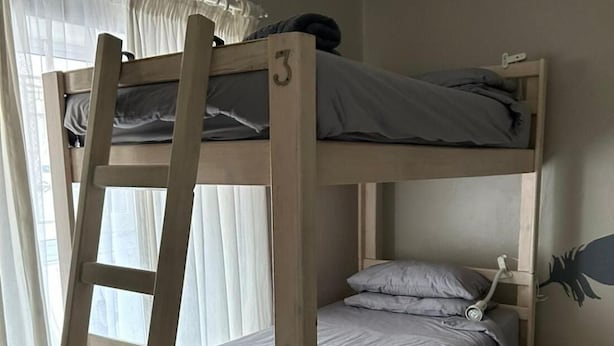 Uma cama beliche com escada, uma gaveta pequena para guardar coisas e uma escrivaninha retrátil.