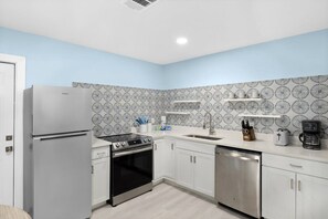 Una cocina moderna con armarios blancos, electrodomésticos de acero inoxidable y un salpicadero con diseño.