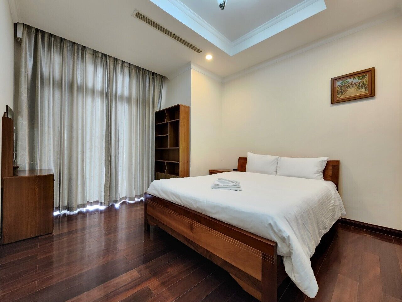 A bedroom with a large bed, wooden headboard, a wardrobe, and a skylight.