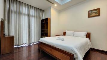 A bedroom with a large bed, wooden headboard, a wardrobe, and a skylight.