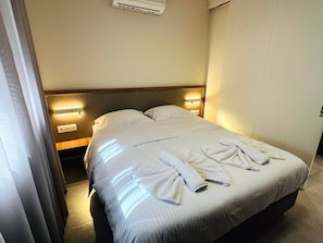 Una habitación de hotel con una cama, dos lámparas de noche y un perchero para toallas.
