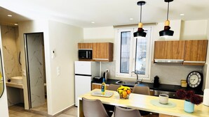 A modern kitchen with a central island, wooden cabinets, a microwave, and a clock on the wall.