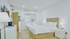 A modern hotel room with a bed, bedside tables, a desk, and a chair.