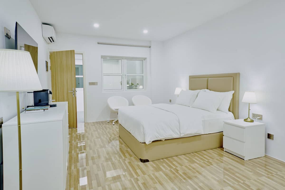 Quarto de hotel moderno com cama, mesas de cabeceira, escrivaninha e uma cadeira.