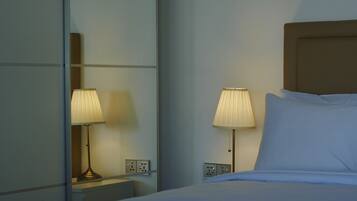 A hotel room with a bed, two bedside lamps, a nightstand, and a mirror.