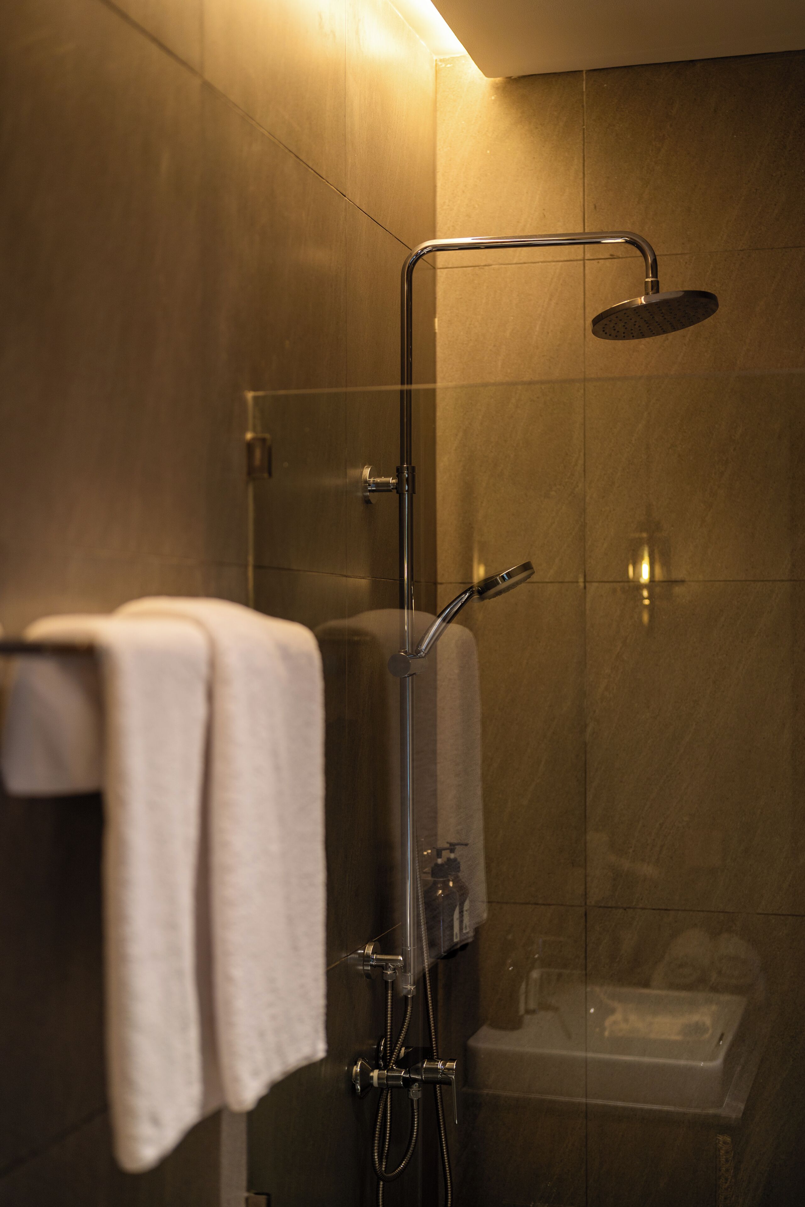 Un baño moderno con ducha de vidrio, una bañera a la vista y un perchero con una toalla.