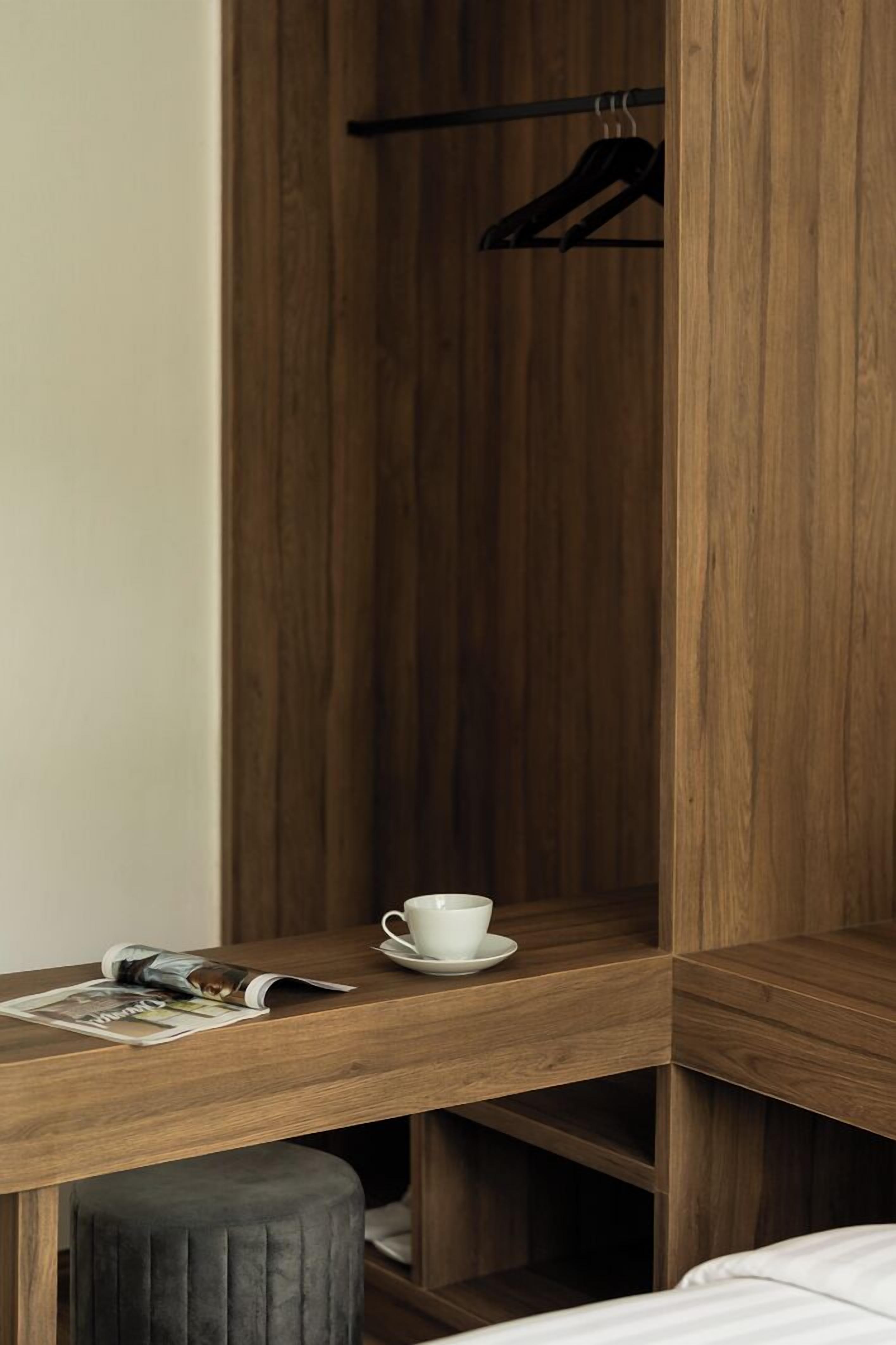 A wooden desk with a cup and saucer, a magazine, and a hanging garment.