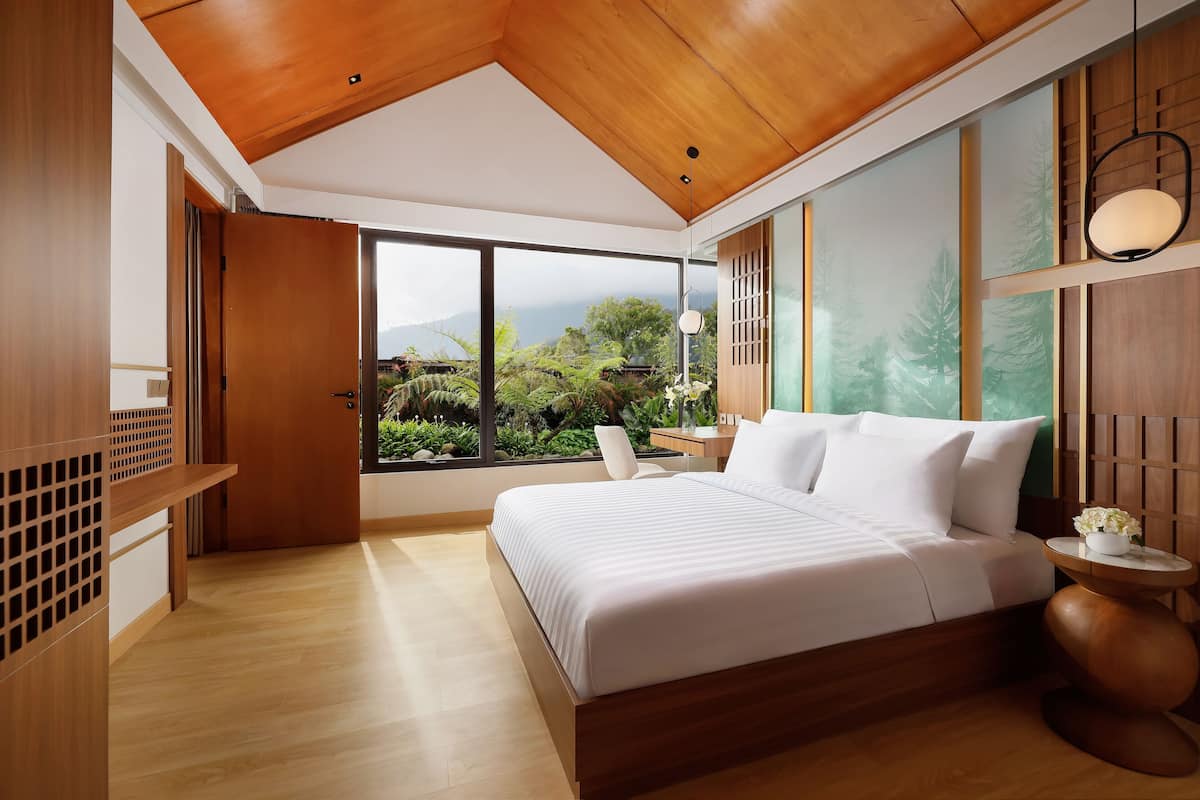 Un dormitorio moderno con una cama grande, techo de madera y vistas a zonas verdes.