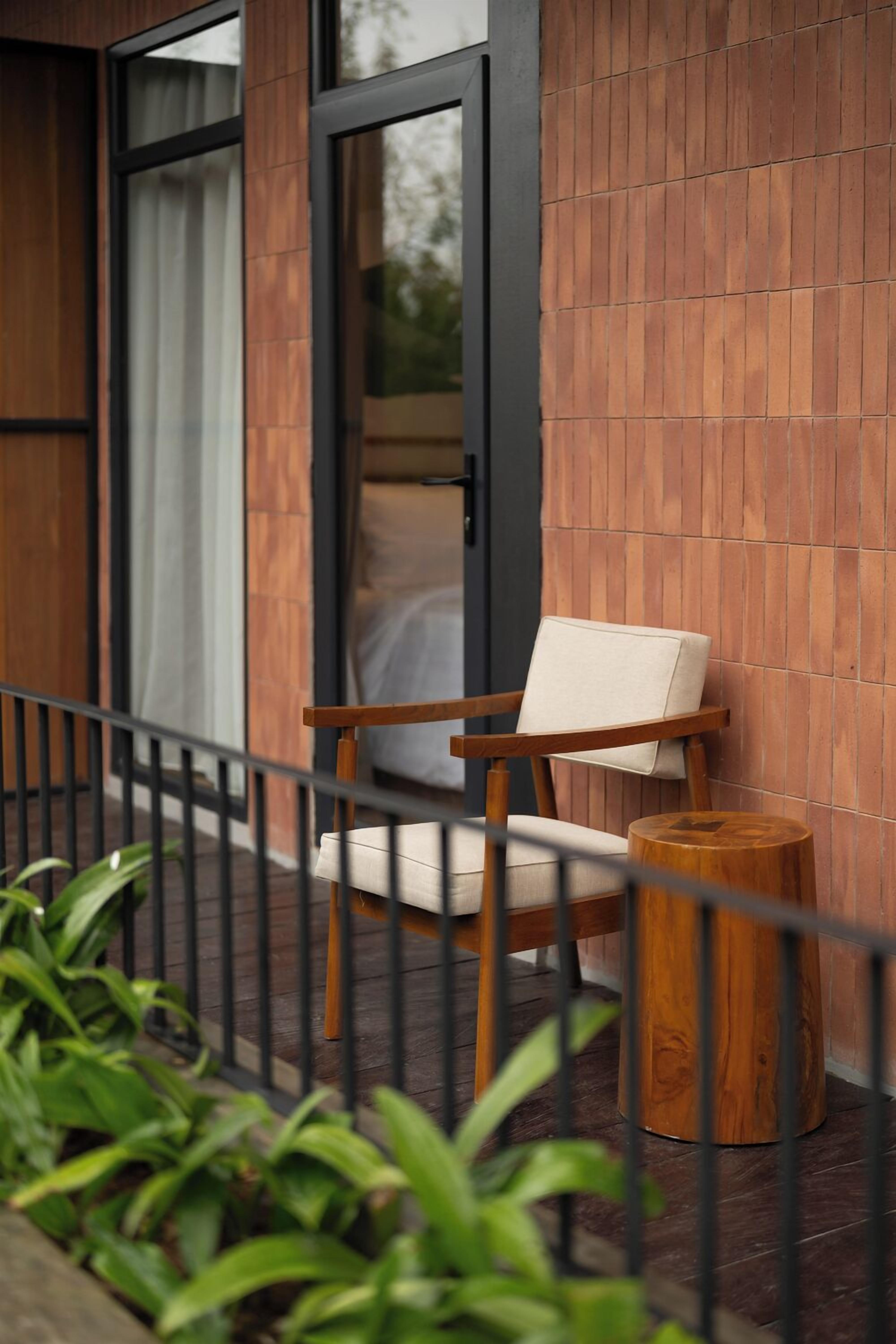 A wooden chair with a cushion on a balcony with a wooden stool.