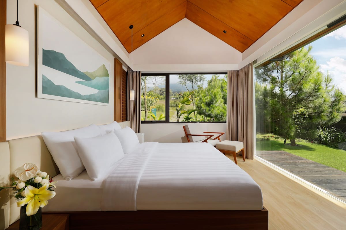 Un dormitorio moderno con una cama grande, una mesa de comedor y vistas a un jardín.