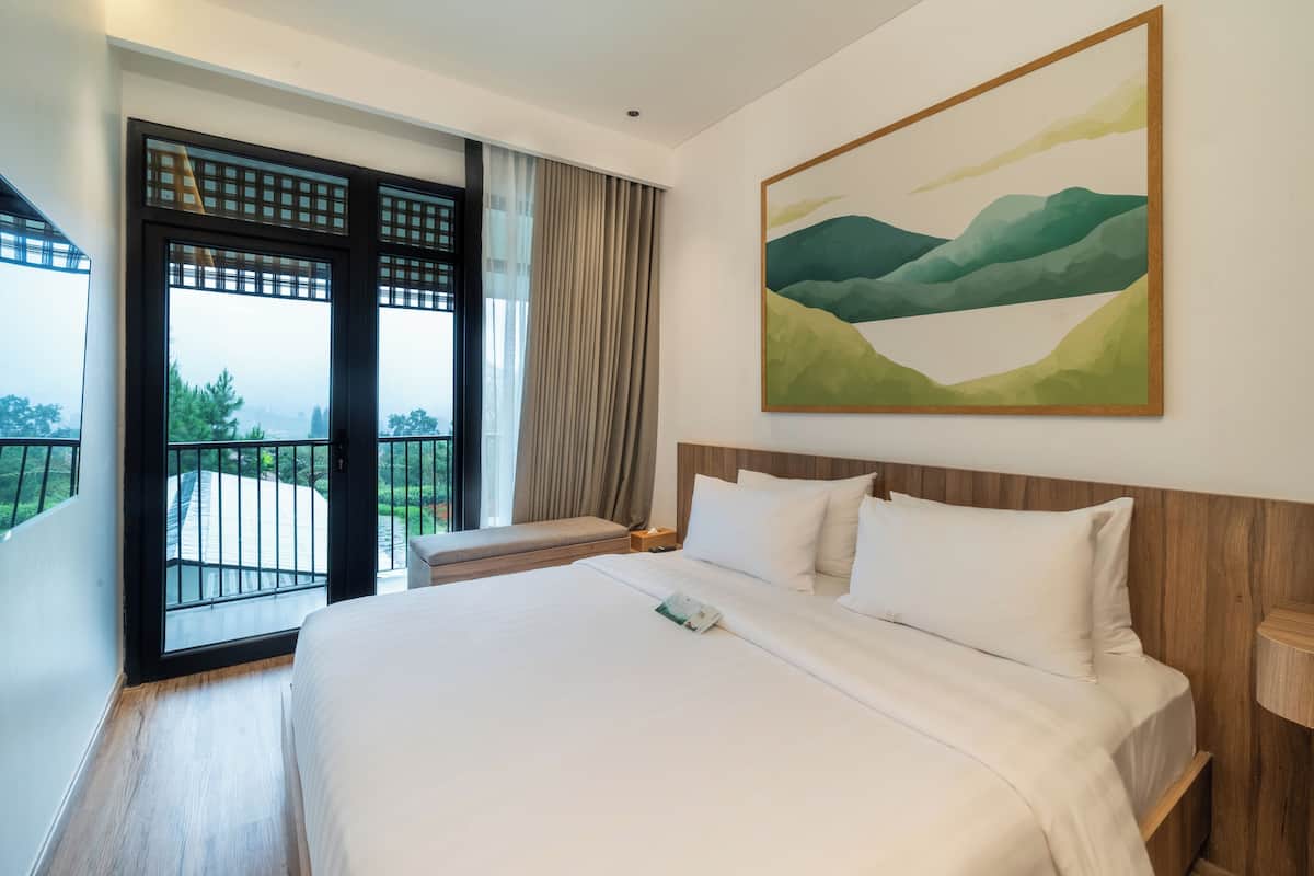 Una habitación de hotel con una cama grande, una ventana con vistas a la vegetación y un cuadro en la pared.