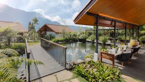Un espace extérieur paisible, doté d’une terrasse en bois, d’un bassin à carpes koï et d’une pancarte indiquant « Bale Cemora ».