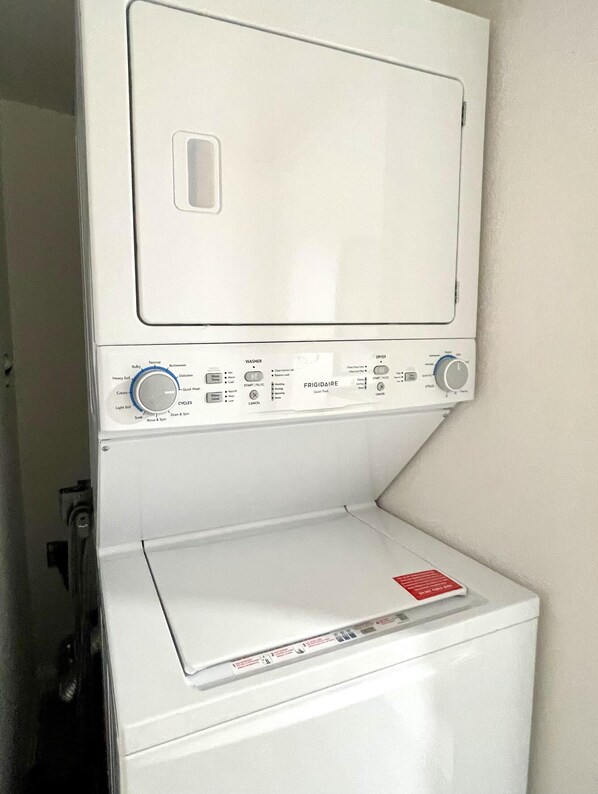 A front-loading washing machine with a control panel, a detergent dispenser, and a label on the door.