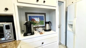 Un angolo cottura con macchina da caffè, bollitore ed un tostapane.